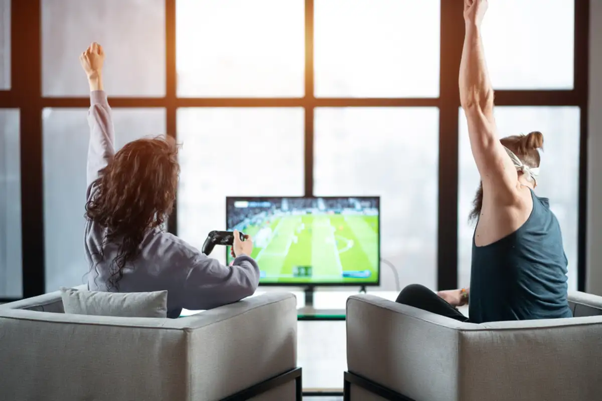 A couple of women sitting in chairs in front of a tv