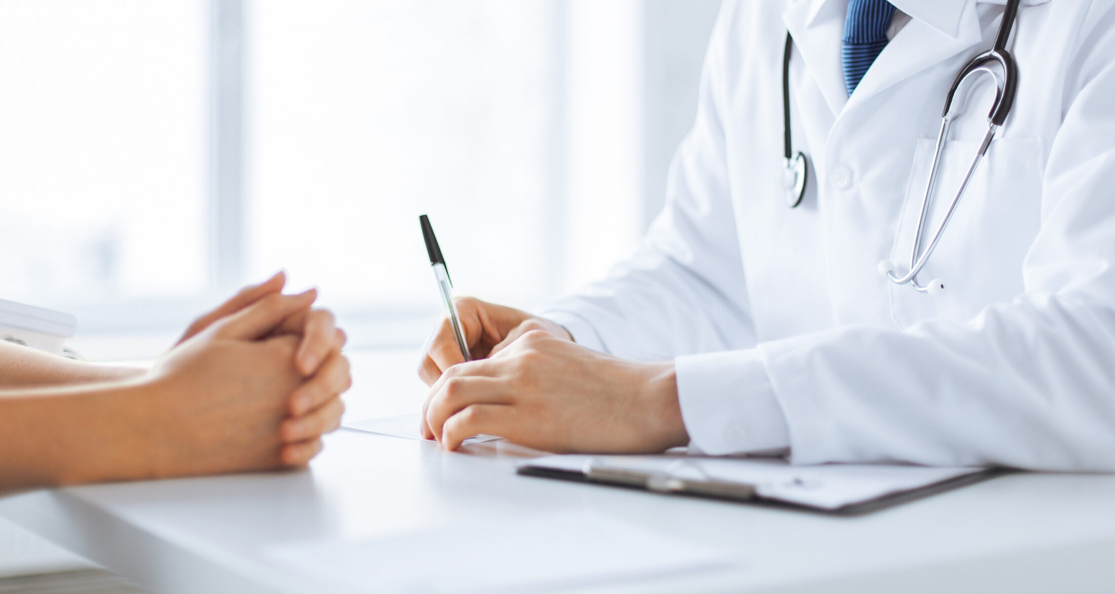 Close Up Of Patient And Doctor Taking Notes